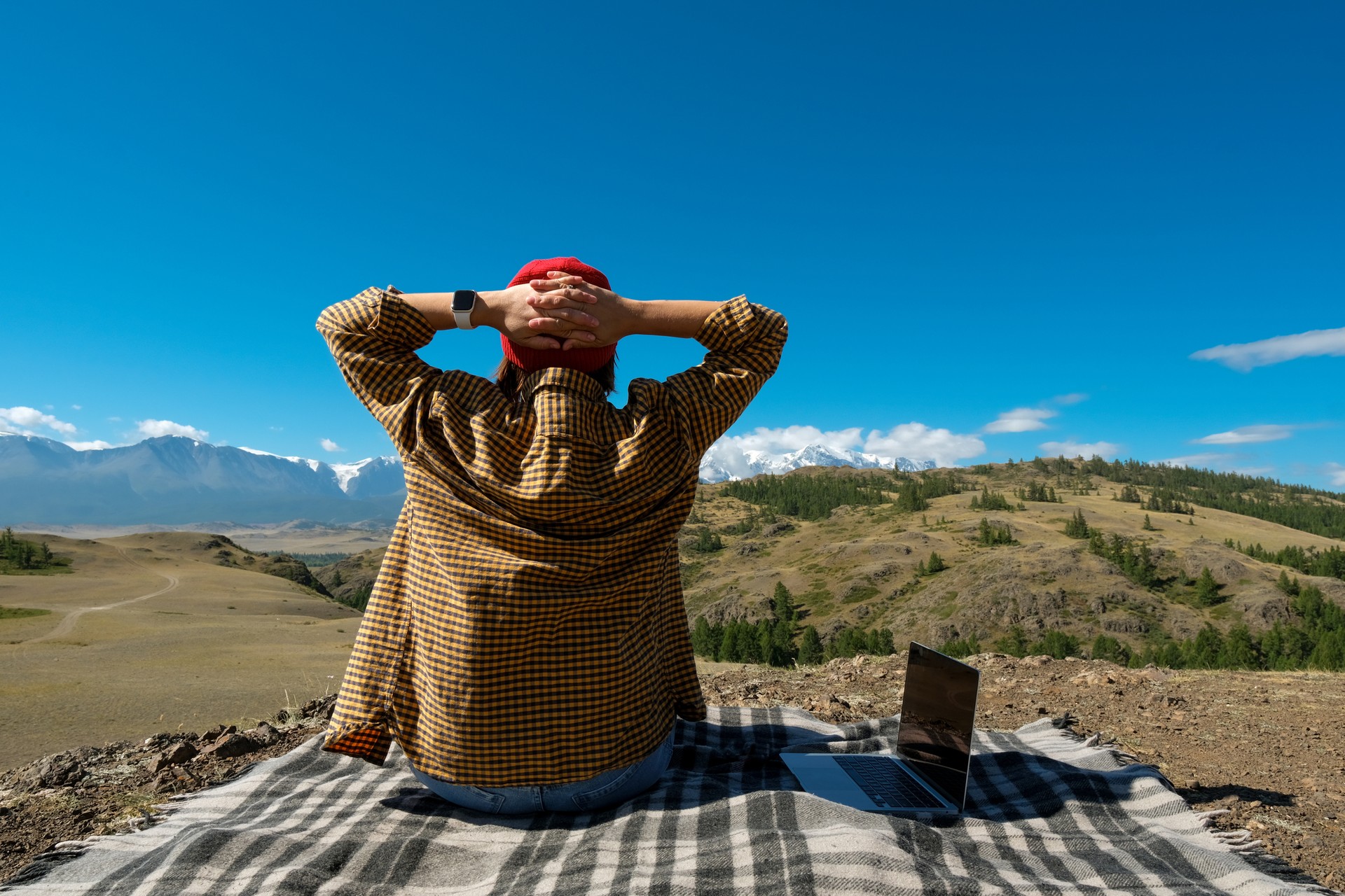woman freelancer traveler working online using laptop and enjoying the beautiful nature landscape with mountain view.
